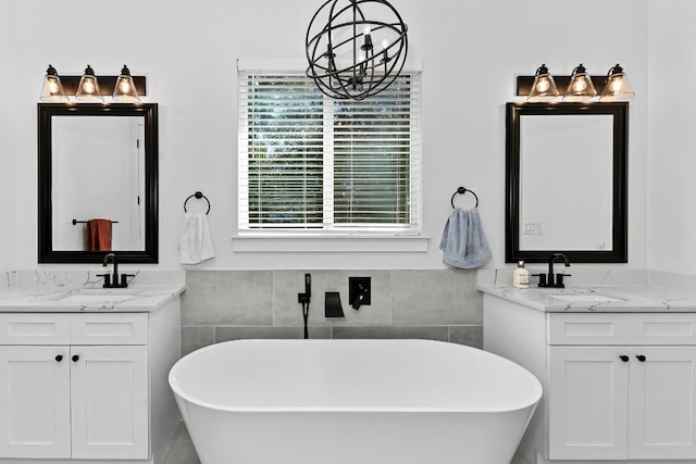 bathroom with a freestanding bath, two vanities, and a sink