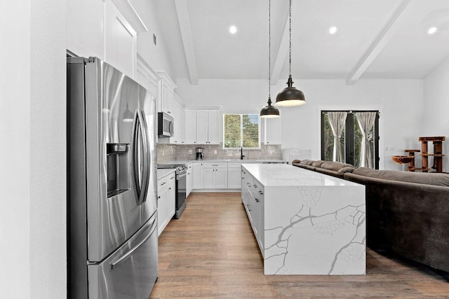101 Saddle Mtn, Boerne, TX 78006 - kitchen featuring appliances with stainless steel finishes, open floor plan, beamed ceiling, a sink, and a kitchen island