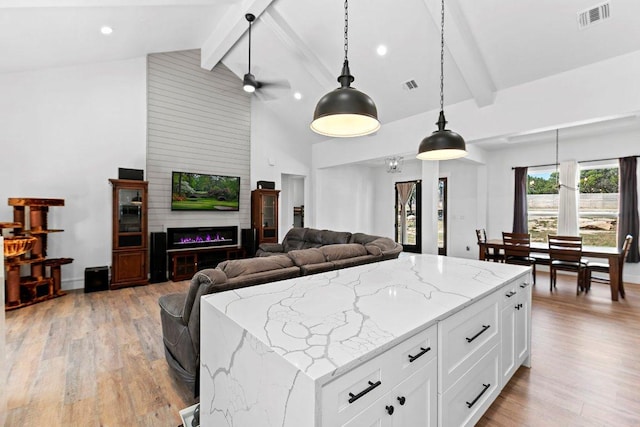 101 Saddle Mtn, Boerne, TX 78006 - kitchen featuring beamed ceiling, light wood-style flooring, hanging light fixtures, open floor plan, and light stone counters