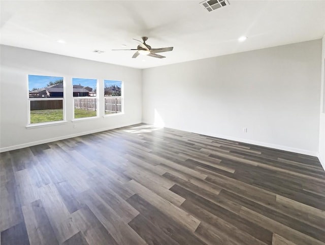 unfurnished room with dark wood-type flooring, visible vents, and baseboards