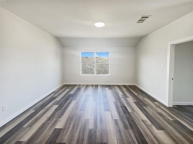 spare room with dark wood-style flooring, visible vents, and baseboards