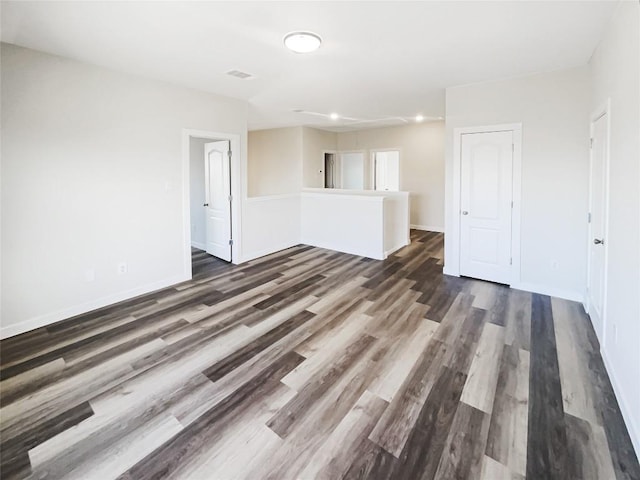 unfurnished room featuring dark wood-type flooring, visible vents, and baseboards