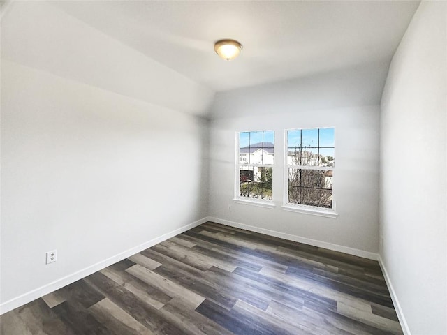 spare room with dark wood-style floors, baseboards, and vaulted ceiling