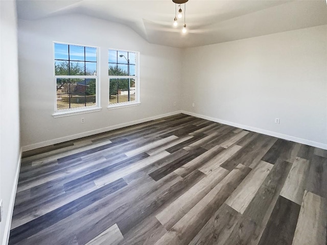 empty room with lofted ceiling, baseboards, and dark wood-type flooring