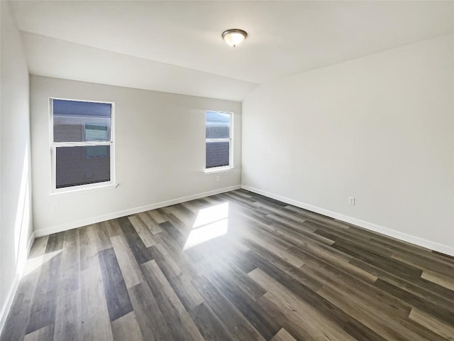 empty room featuring baseboards and dark wood finished floors