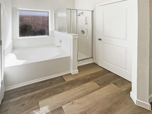 full bath featuring a bath, a shower stall, and wood finished floors