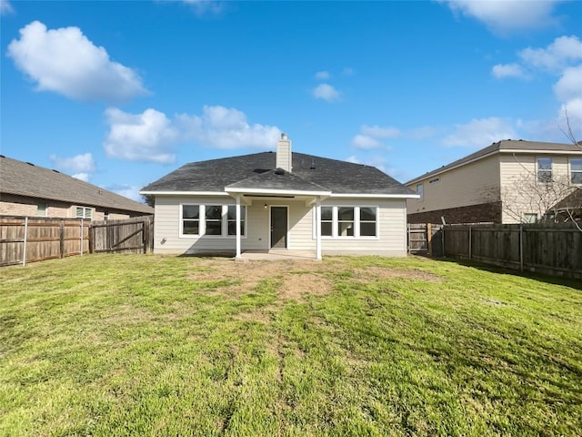 rear view of house featuring a fenced backyard, a yard, and a chimney