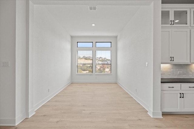 unfurnished dining area featuring light wood finished floors, visible vents, and baseboards