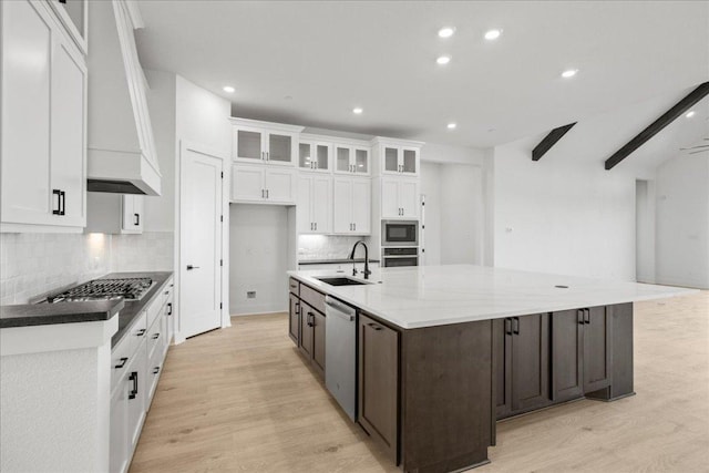 kitchen with light wood finished floors, appliances with stainless steel finishes, a sink, and white cabinetry