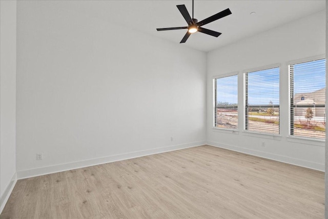 spare room with a ceiling fan, light wood-type flooring, and baseboards