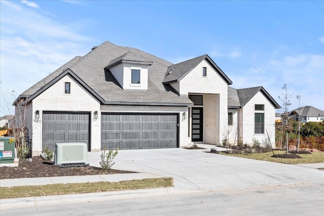 view of front of property featuring brick siding, a shingled roof, central AC, and concrete driveway