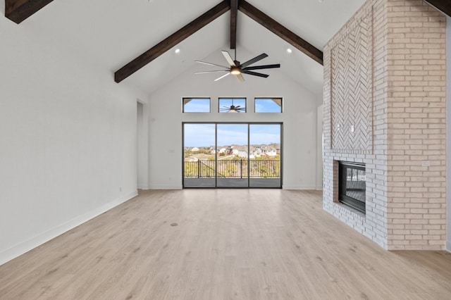 unfurnished living room featuring baseboards, wood finished floors, beamed ceiling, a fireplace, and high vaulted ceiling