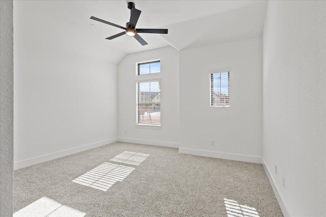 spare room featuring a ceiling fan, light carpet, vaulted ceiling, and baseboards