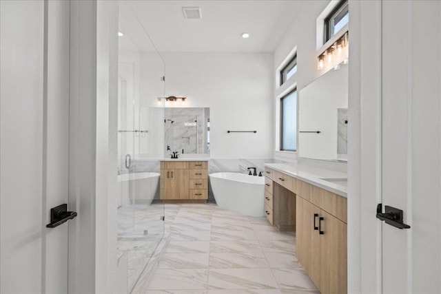 full bathroom with marble finish floor, a shower stall, two vanities, and a soaking tub