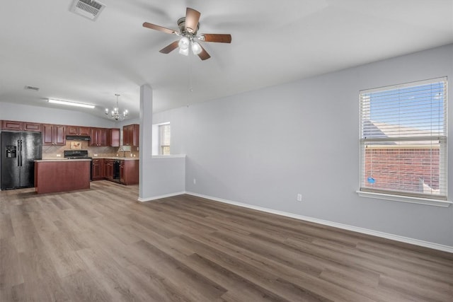 interior space featuring visible vents, open floor plan, under cabinet range hood, black appliances, and backsplash