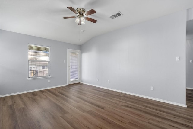 spare room with lofted ceiling, wood finished floors, visible vents, and baseboards