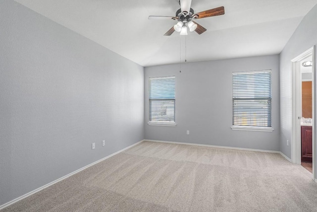 unfurnished room featuring lofted ceiling, light colored carpet, a sink, a ceiling fan, and baseboards