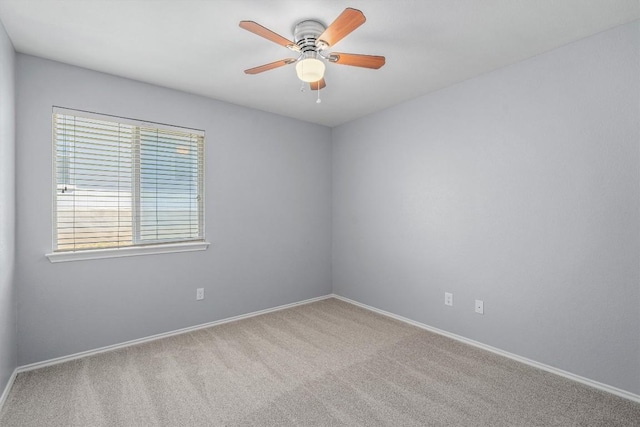 carpeted empty room featuring a ceiling fan and baseboards