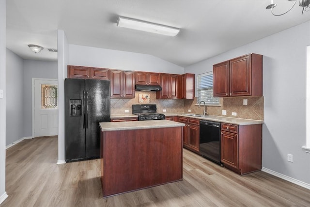 kitchen featuring light wood-style flooring, under cabinet range hood, light countertops, black appliances, and a sink