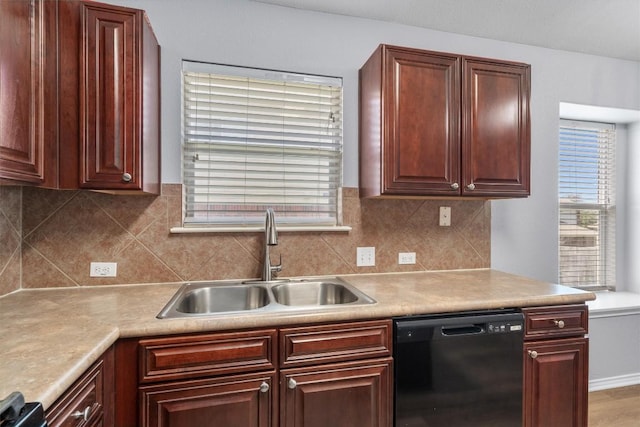 kitchen with black dishwasher, light countertops, backsplash, and a sink