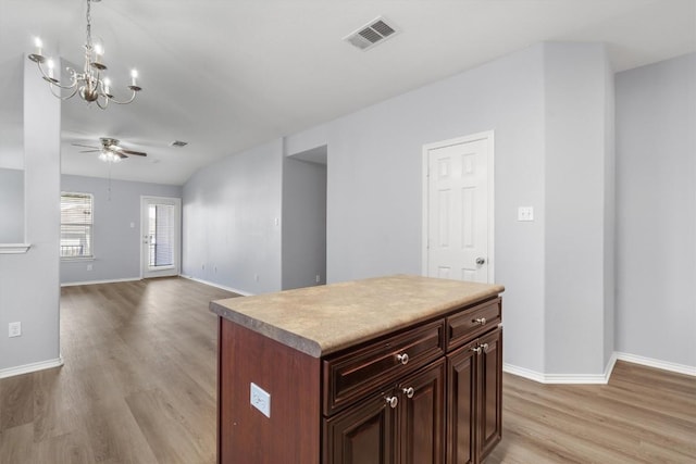 kitchen with light wood-style flooring, ceiling fan with notable chandelier, visible vents, baseboards, and decorative light fixtures