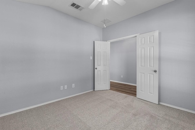 carpeted empty room featuring visible vents, vaulted ceiling, baseboards, and ceiling fan