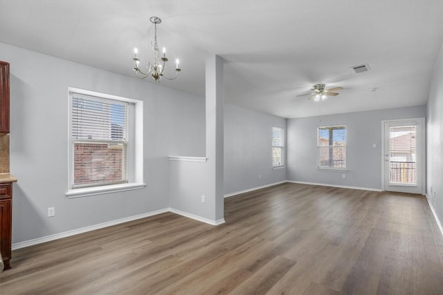 interior space featuring ceiling fan with notable chandelier, visible vents, baseboards, and wood finished floors