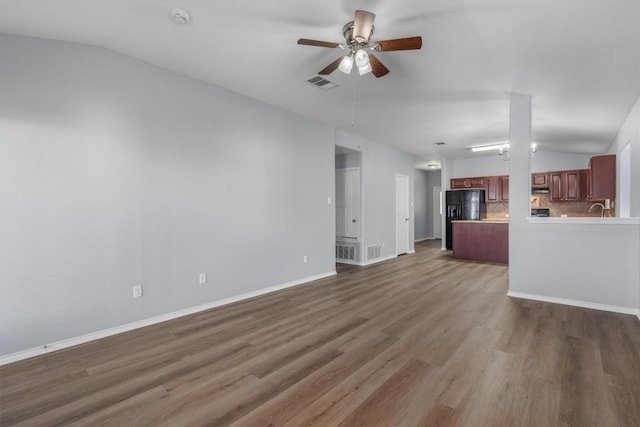 unfurnished living room featuring lofted ceiling, ceiling fan, visible vents, and wood finished floors