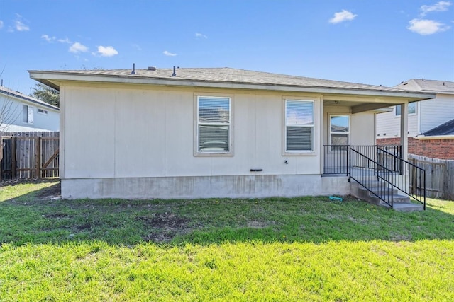 back of property featuring fence and a lawn