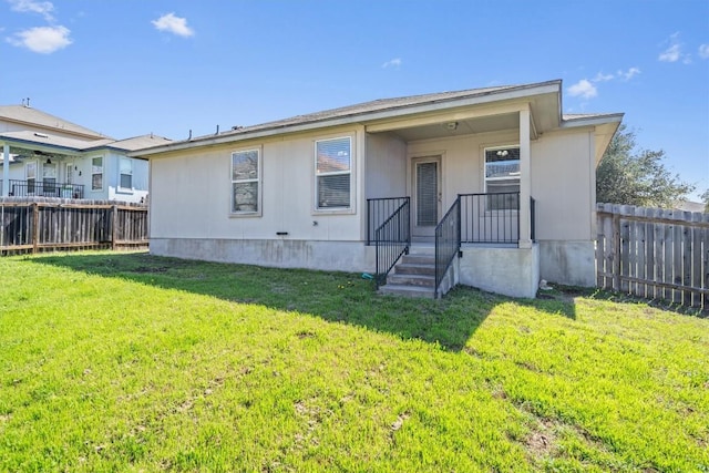 rear view of house featuring a yard and fence