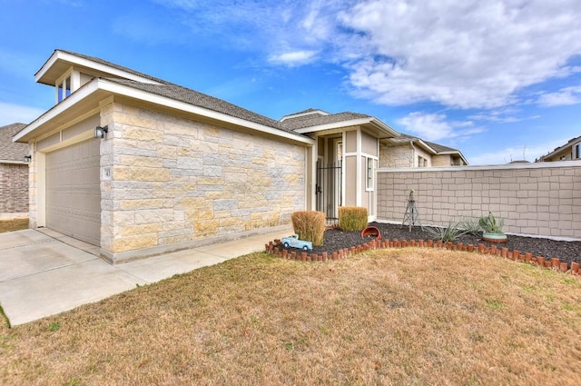 view of front of property featuring an attached garage, stone siding, fence, and a front yard