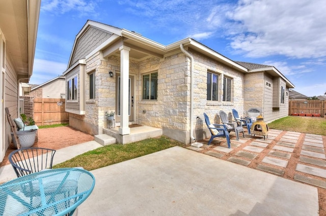 back of property with stone siding, a patio area, and a fenced backyard