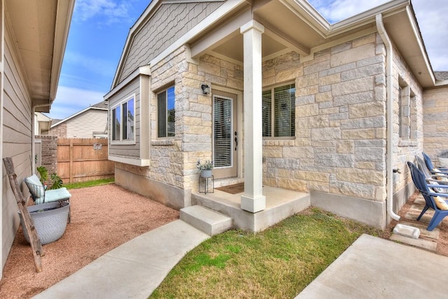 property entrance featuring stone siding and fence