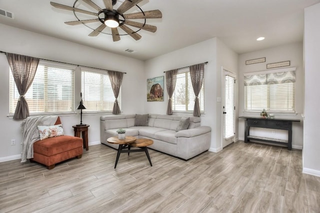 living area with light wood-style floors, visible vents, baseboards, and a ceiling fan