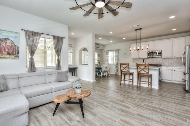 living area featuring light wood-style flooring, recessed lighting, visible vents, baseboards, and a ceiling fan