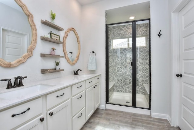 bathroom with double vanity, a stall shower, and a sink