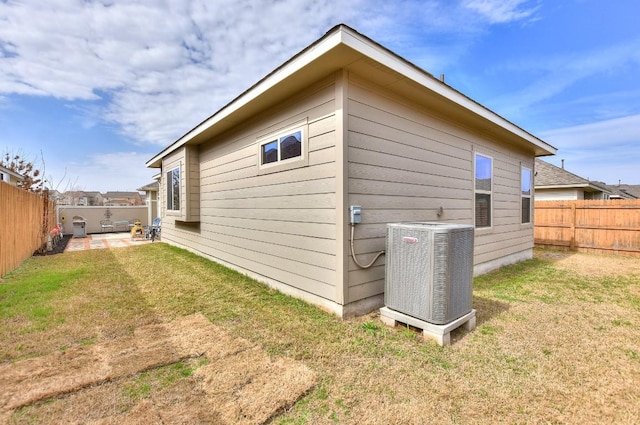 view of home's exterior with central AC, a lawn, and a fenced backyard