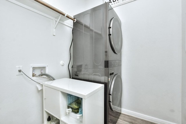 laundry room featuring stacked washer / dryer, laundry area, baseboards, and wood finished floors