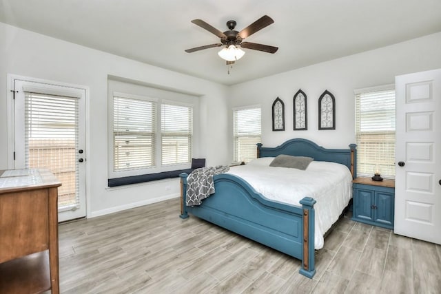 bedroom with light wood-style floors, multiple windows, and baseboards