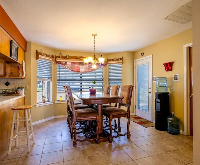 dining room with light tile patterned flooring, visible vents, baseboards, and an inviting chandelier