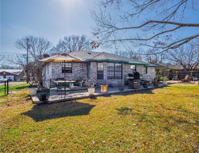 rear view of property featuring a patio area, a yard, brick siding, and fence