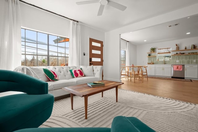 living area with light wood-type flooring, visible vents, ceiling fan, and recessed lighting