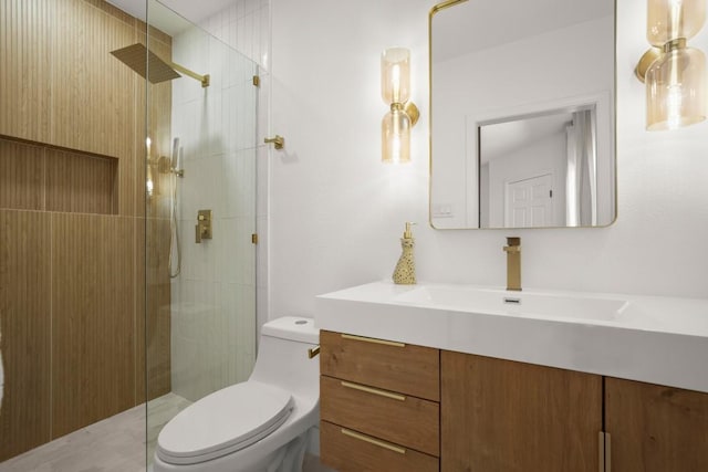 bathroom with toilet, a tile shower, and vanity