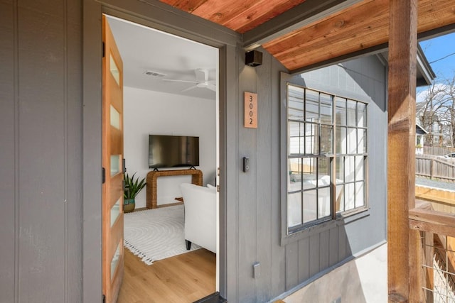 doorway to outside with ceiling fan, a wealth of natural light, beamed ceiling, and wood finished floors