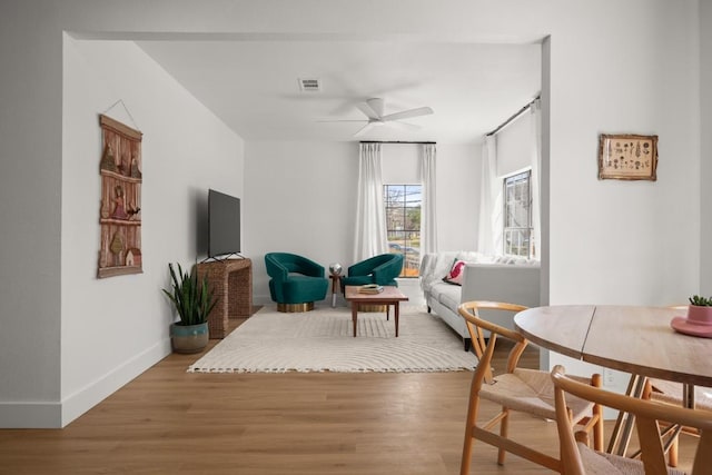 sitting room with ceiling fan, wood finished floors, visible vents, and baseboards