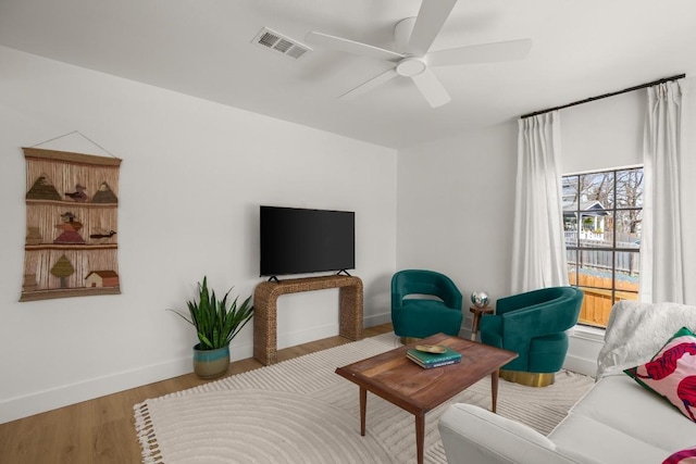 living area with baseboards, ceiling fan, visible vents, and wood finished floors