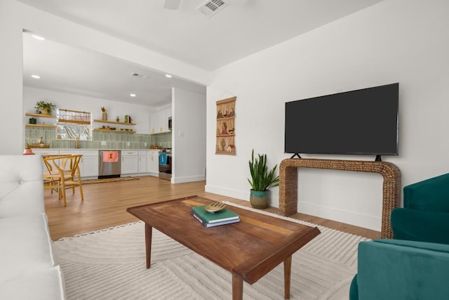 living area with light wood finished floors, baseboards, visible vents, and recessed lighting