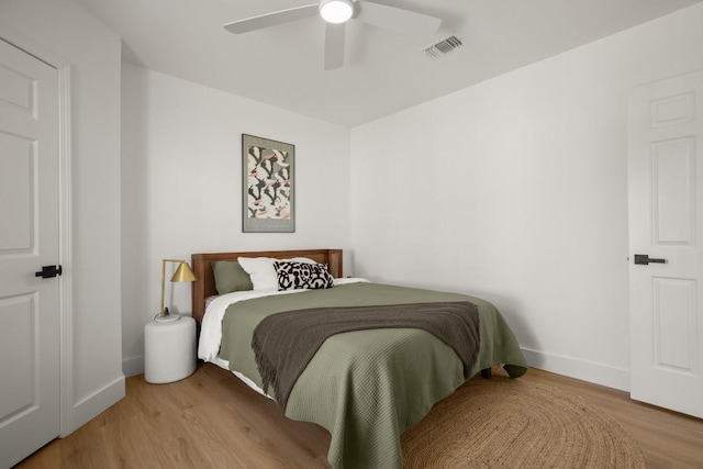 bedroom featuring light wood-style flooring, visible vents, ceiling fan, and baseboards