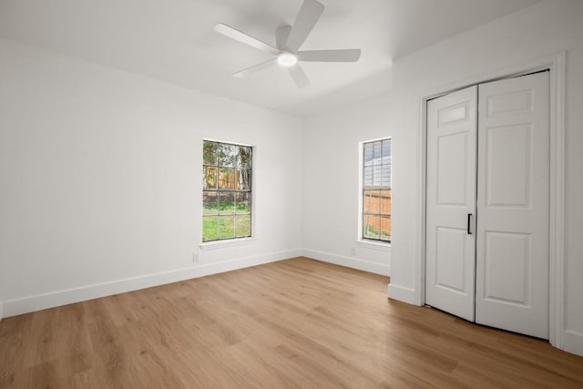 unfurnished bedroom featuring light wood-type flooring, multiple windows, ceiling fan, and baseboards