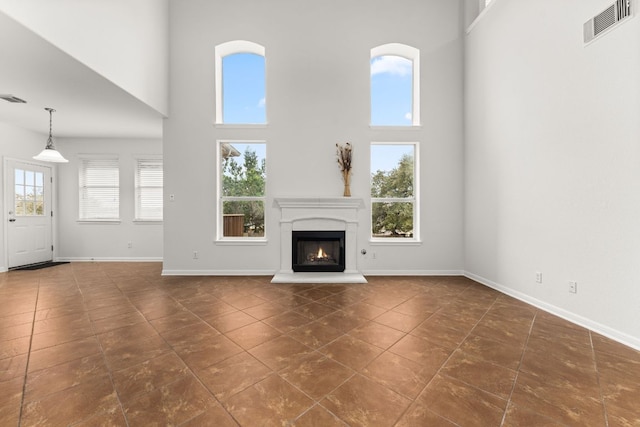 unfurnished living room with plenty of natural light, visible vents, and baseboards